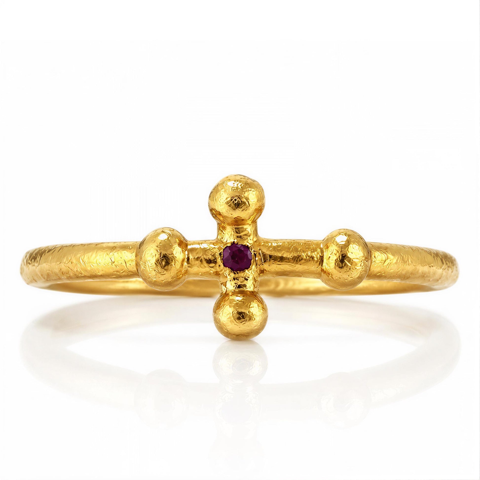 A gold ring with a cross-shaped gemstone in the center.
