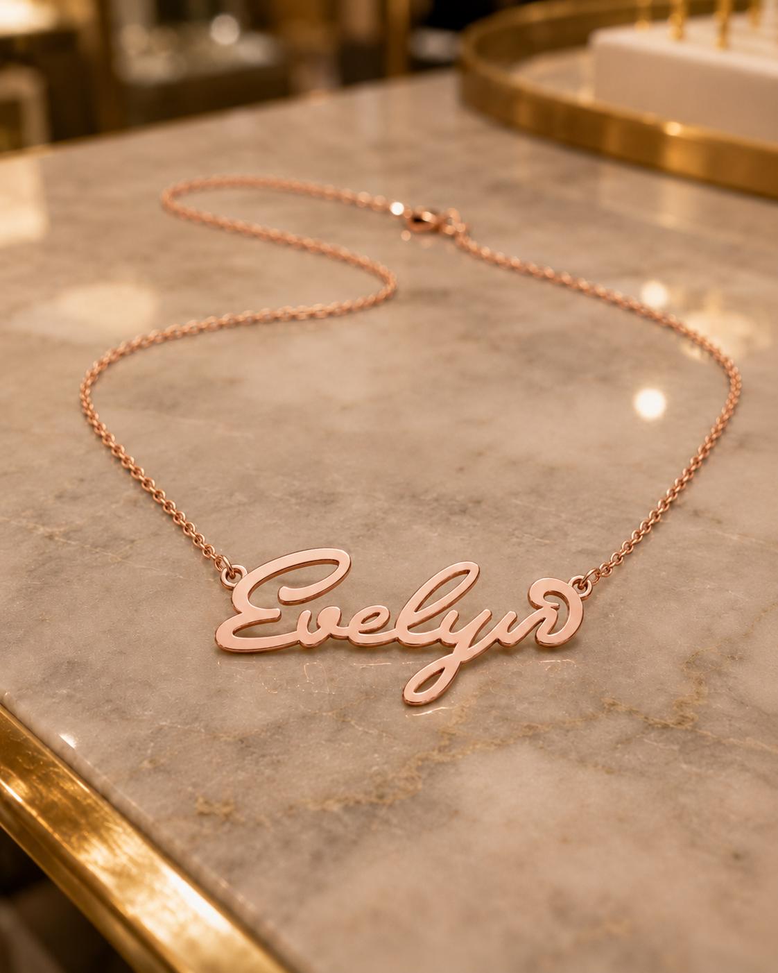 A necklace with the name "Evelyn" engraved on it, resting on a marble surface.