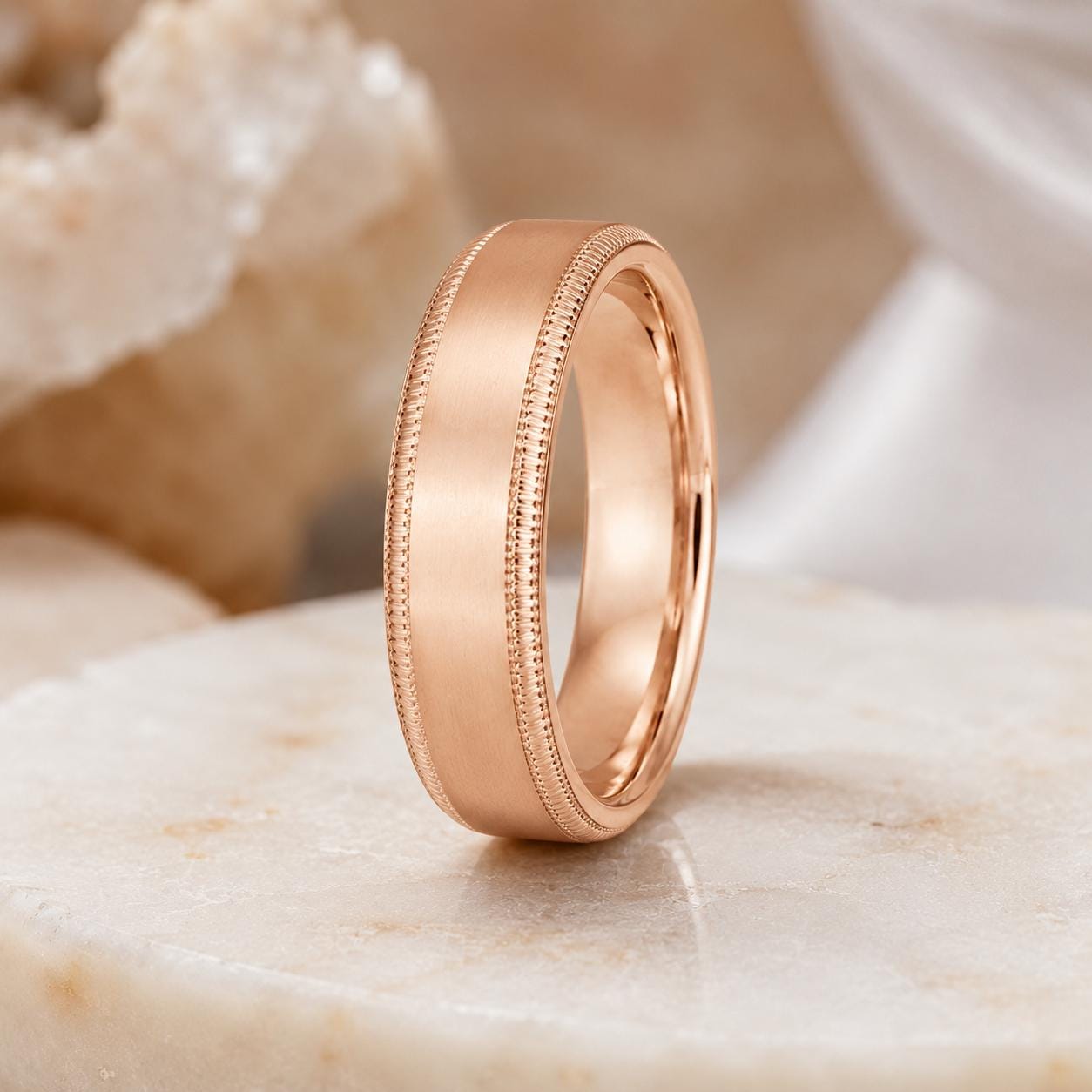 A gold-colored ring with a smooth, polished finish sits on a white marble surface.