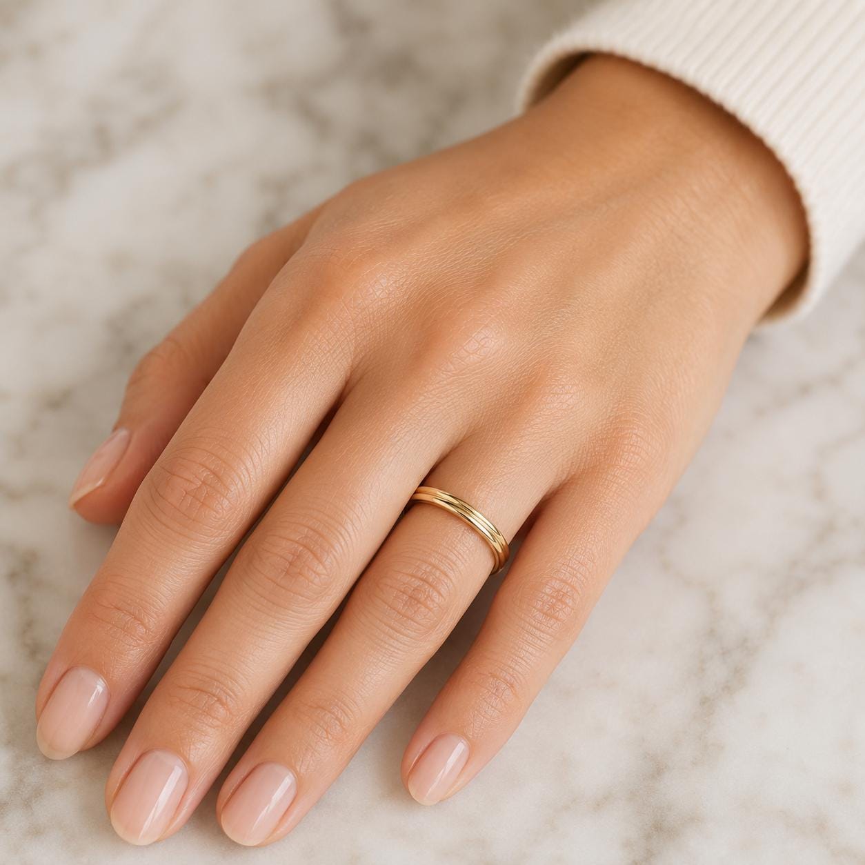 A close-up view of a hand wearing a gold ring on the ring finger.