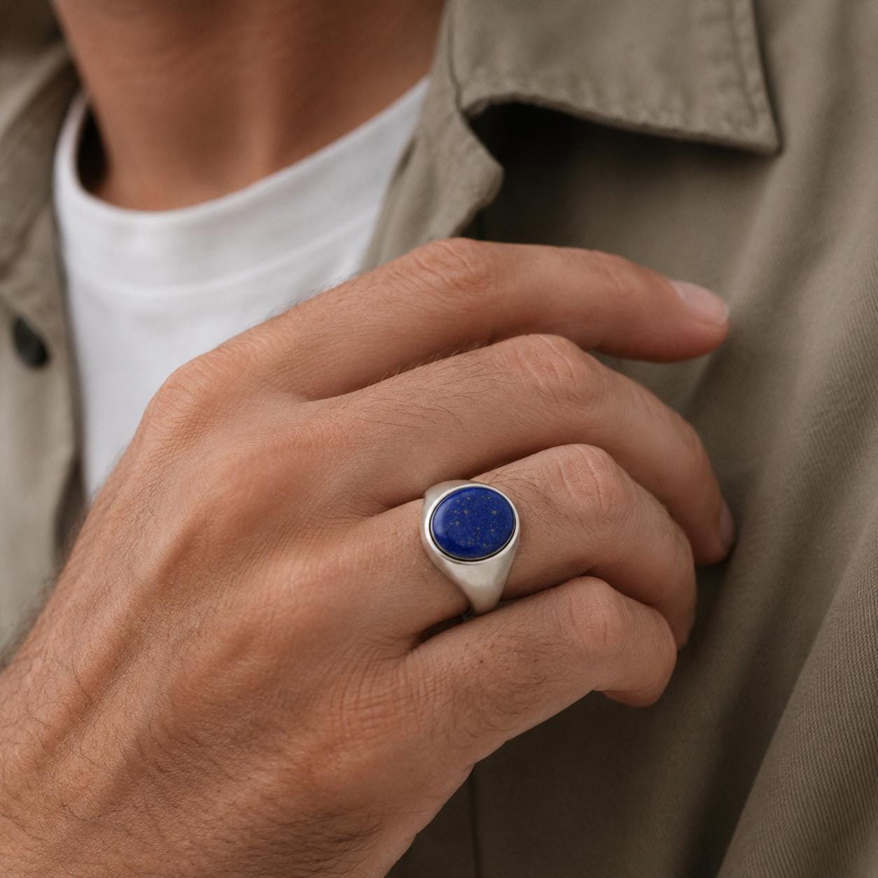 A close-up of a person's hand wearing a silver ring with a blue lapis lazuli stone.