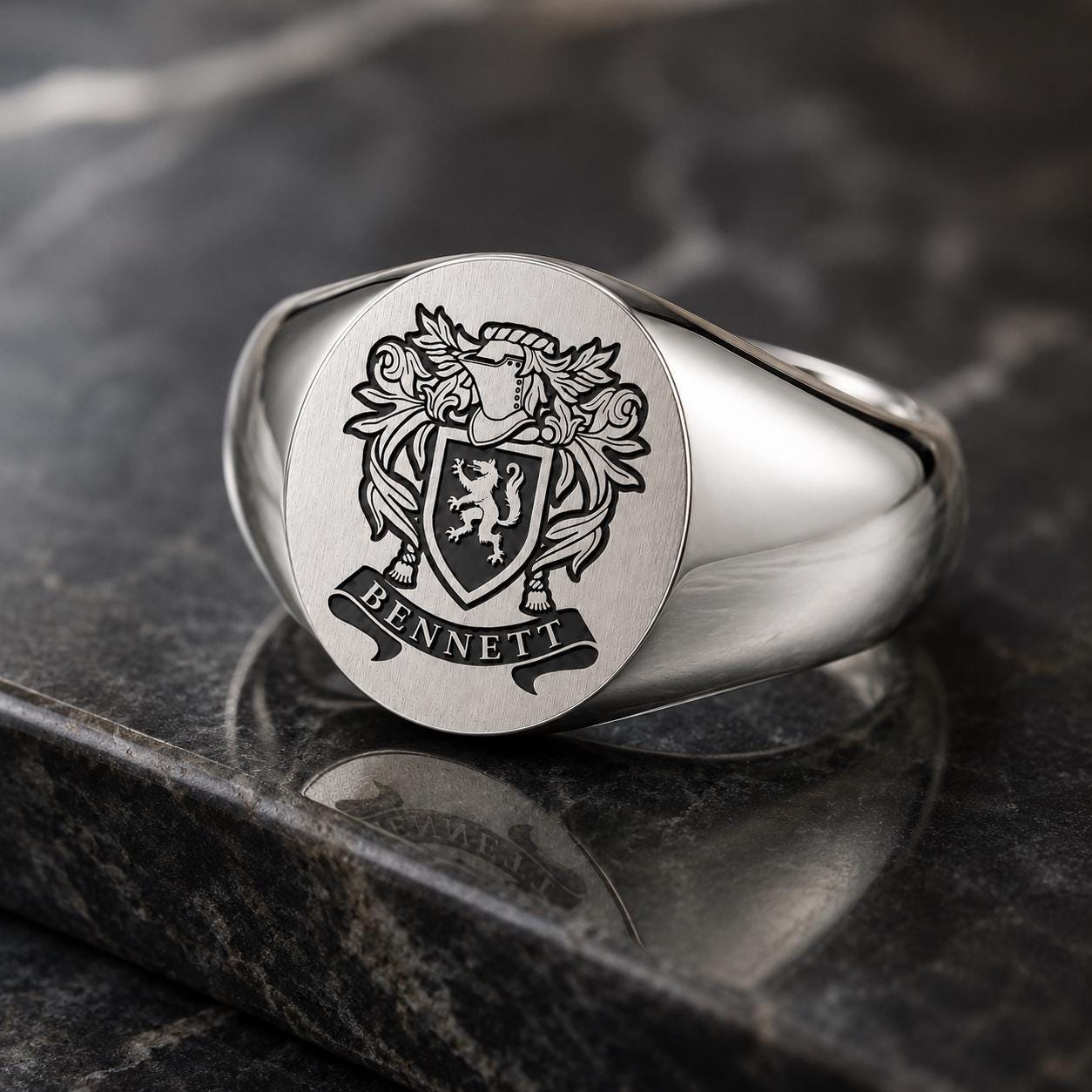 A silver ring with a crest and the word "BENNETT" engraved on it.