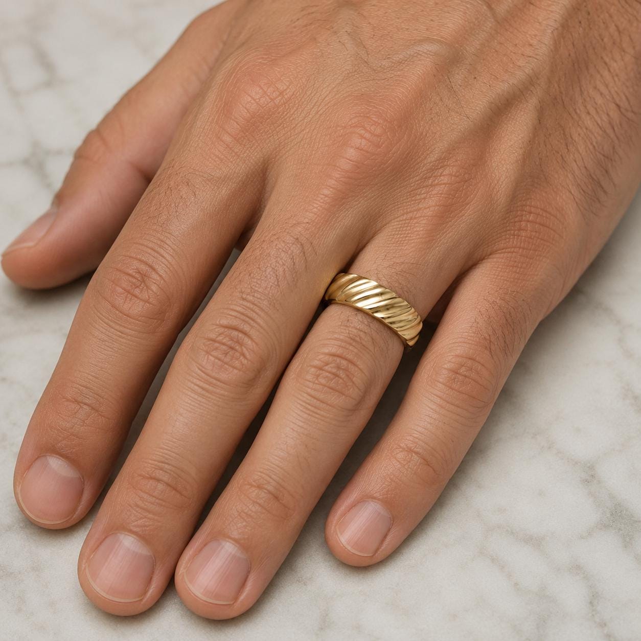 A close-up image of a person's hand wearing a gold ring on the ring finger.