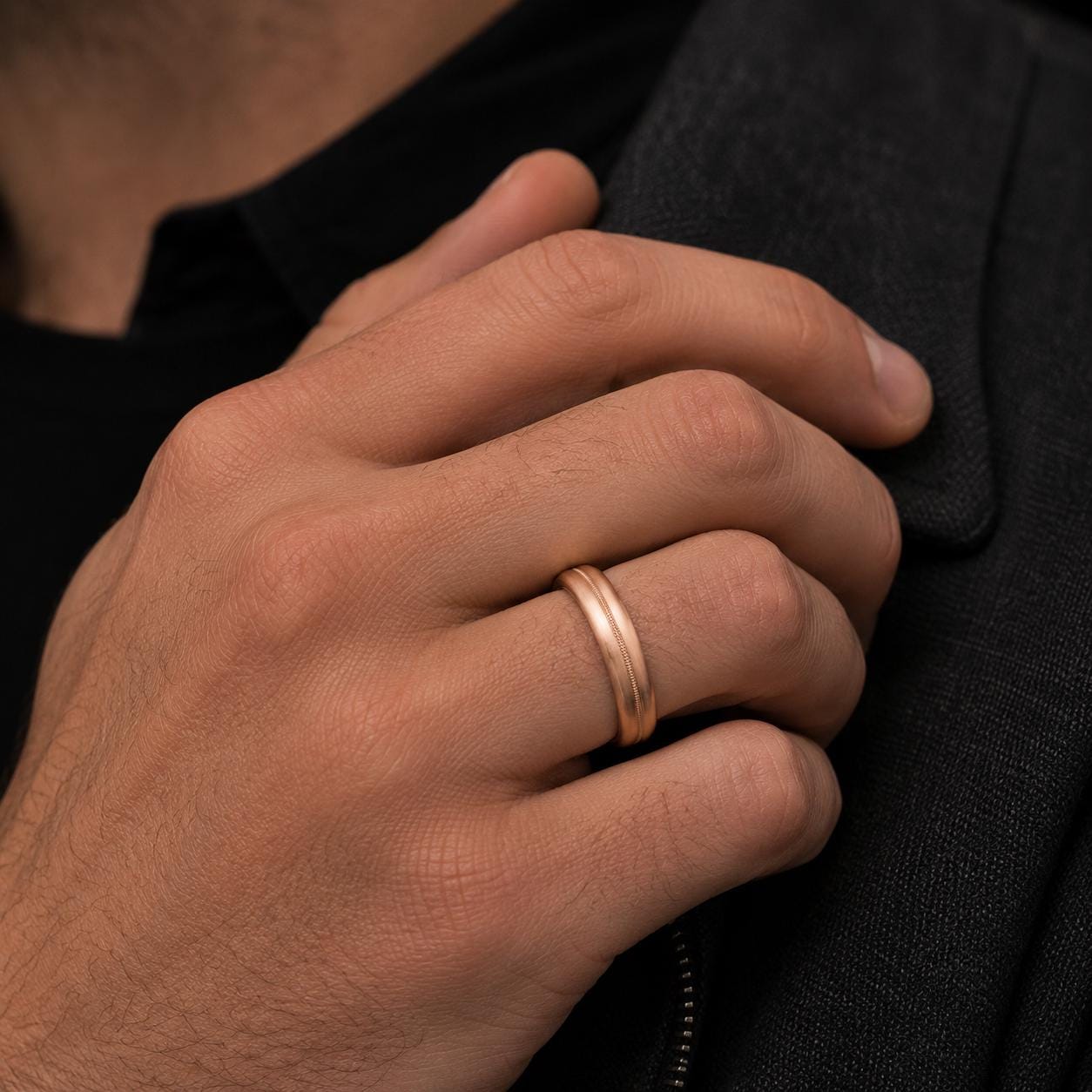 A close-up of a person's hand wearing a gold wedding ring.