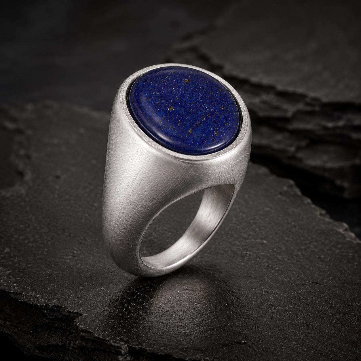 A silver ring with a blue lapis lazuli stone set in the center, resting on a dark surface.