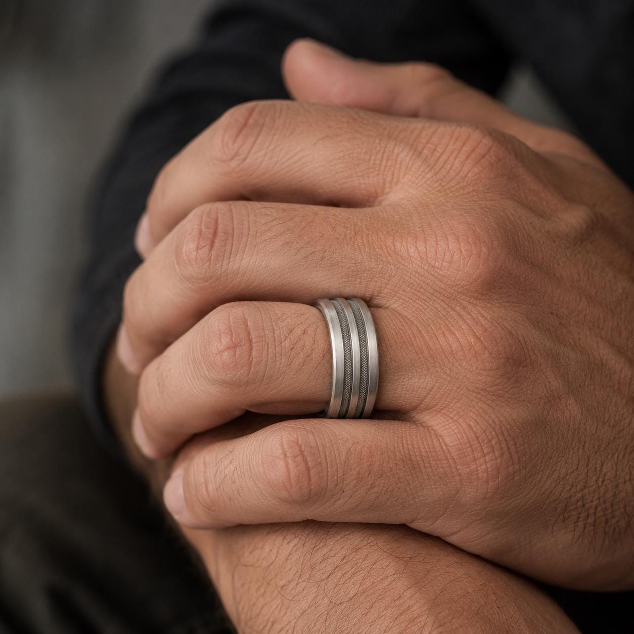 A close-up image of a person's hand wearing a silver ring on the ring finger.