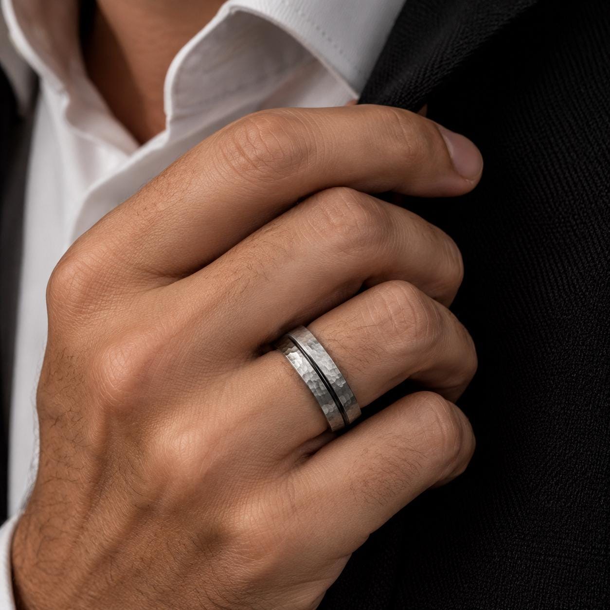 A close-up of a person's hand wearing a silver ring on the ring finger.