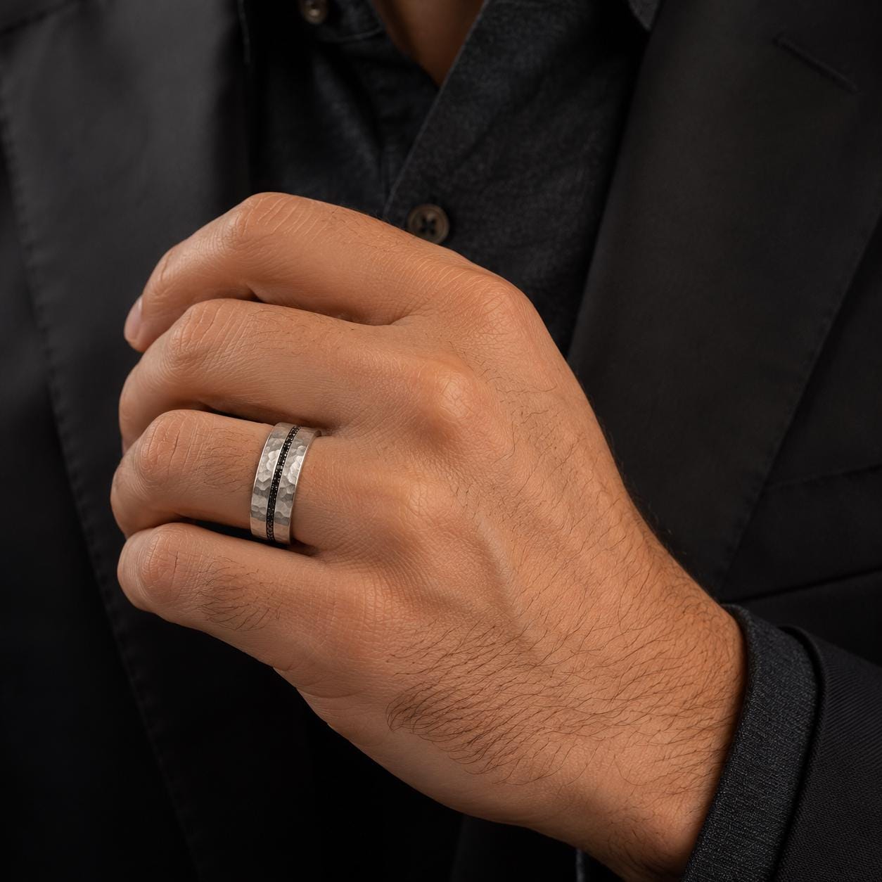 A close-up of a person's hand wearing a silver ring on the ring finger.