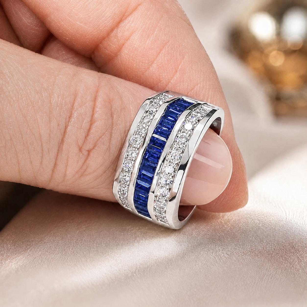 A close-up of a person's hand wearing a silver ring with blue and white gemstones.