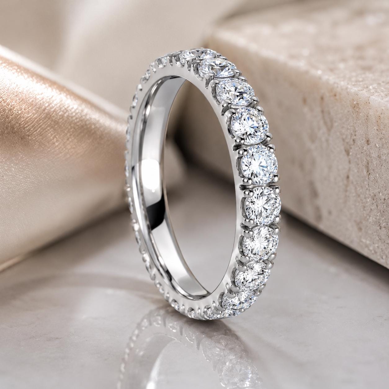A diamond-encrusted ring with a row of diamonds set in a silver band, resting on a marble surface.