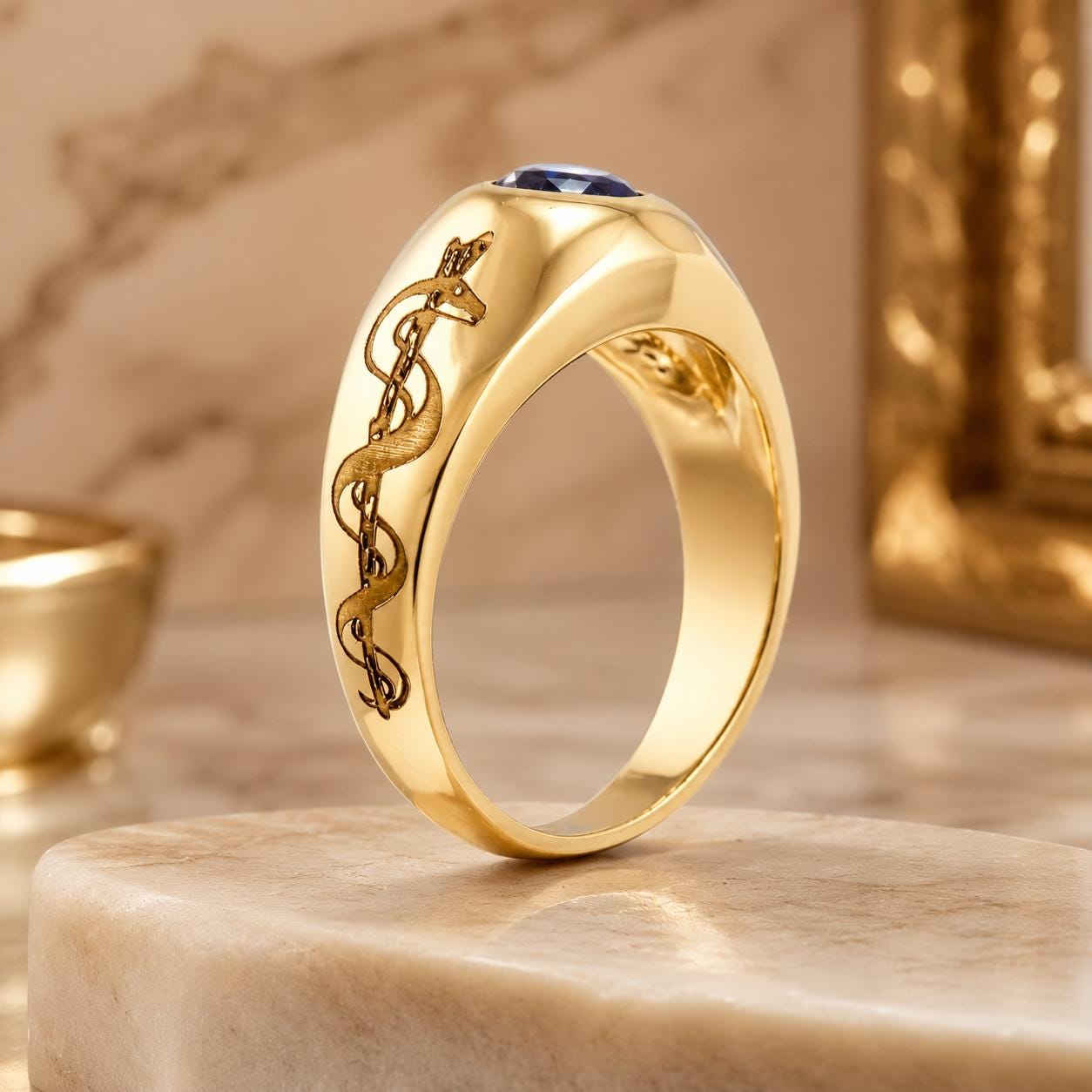 A gold ring with a blue gemstone, featuring a snake design, is displayed on a marble surface.