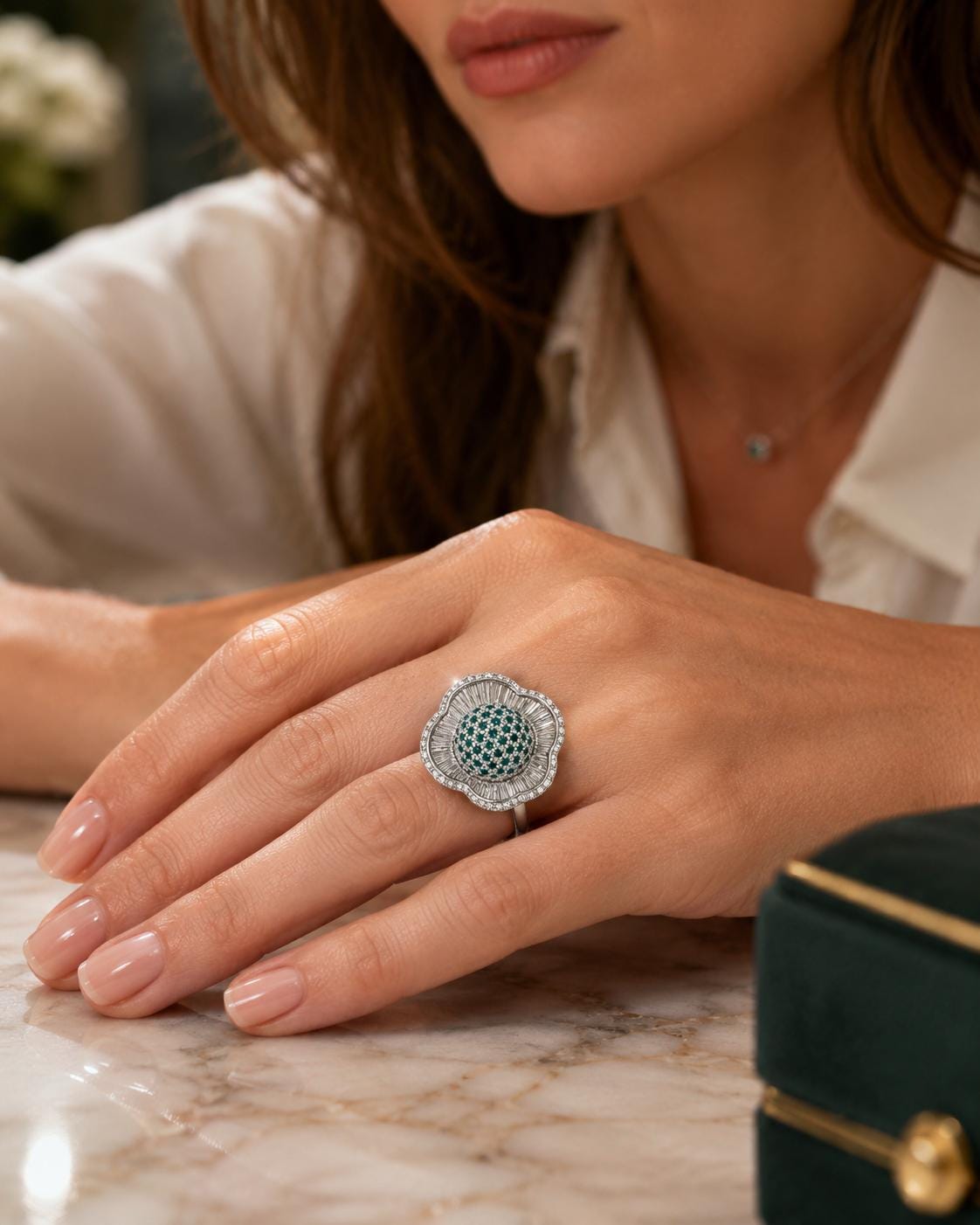 A close-up of a woman's hand wearing a large, ornate ring with a green gemstone.