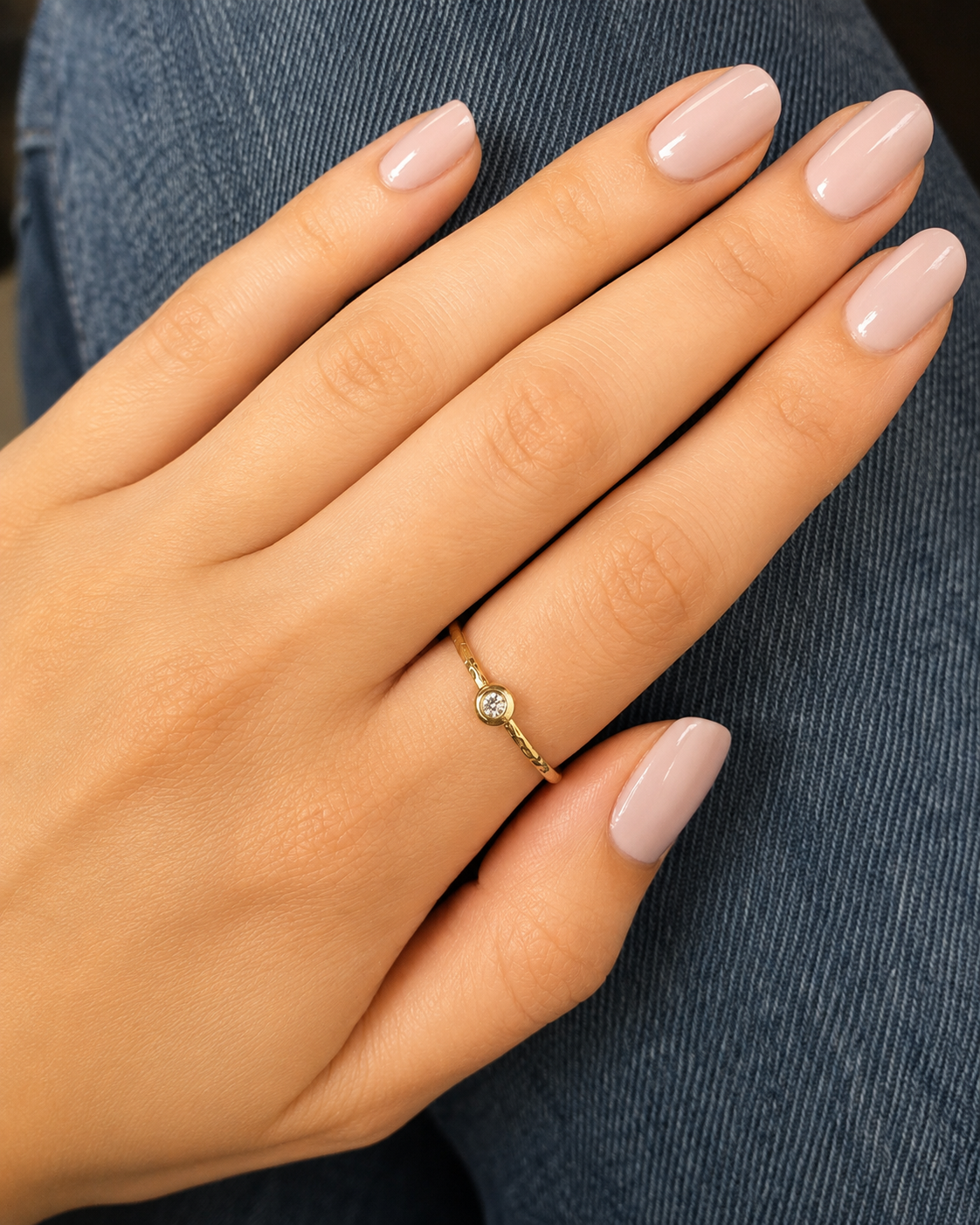 A close-up of a person's hand wearing a gold ring with a small diamond.