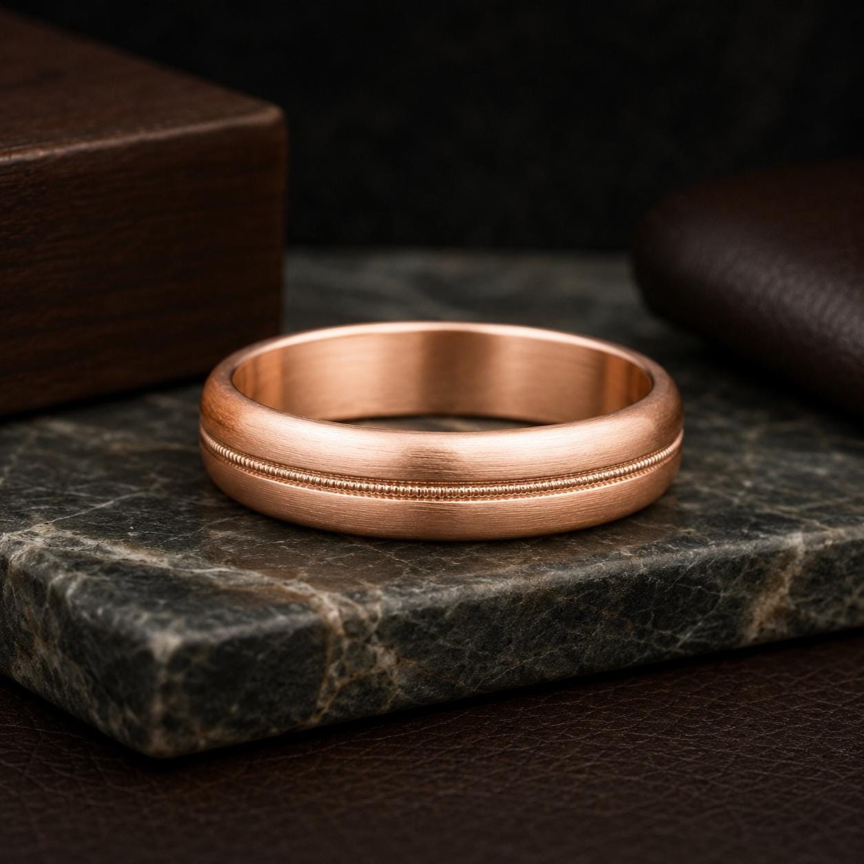 A copper-colored ring is displayed on a dark surface, surrounded by other objects.