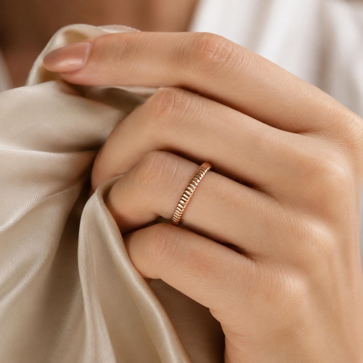 A close-up image of a person's hand wearing a gold ring on the ring finger.