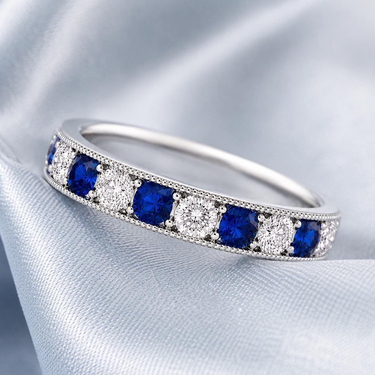 A silver ring with a row of blue sapphires and diamonds set in a decorative pattern.