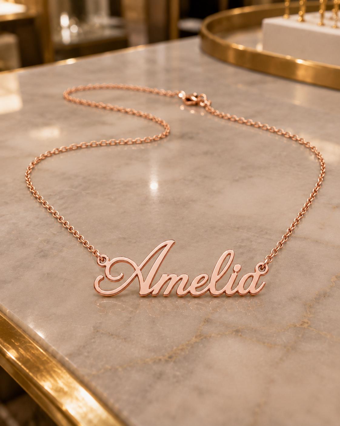 A necklace with the name "Amelia" engraved on it, resting on a marble surface.