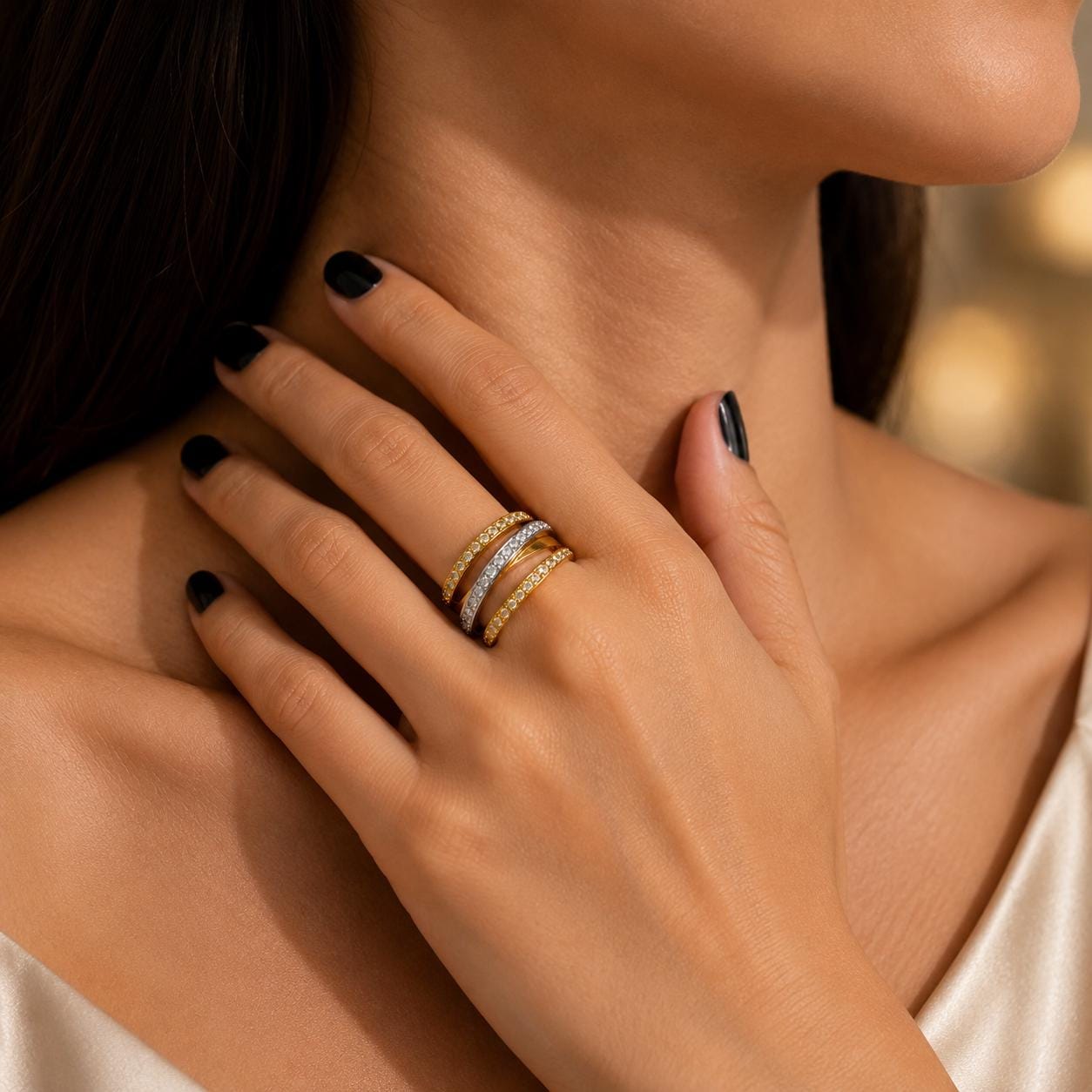 A close-up of a woman's hand wearing a gold ring with multiple tiers, resting on her hand.
