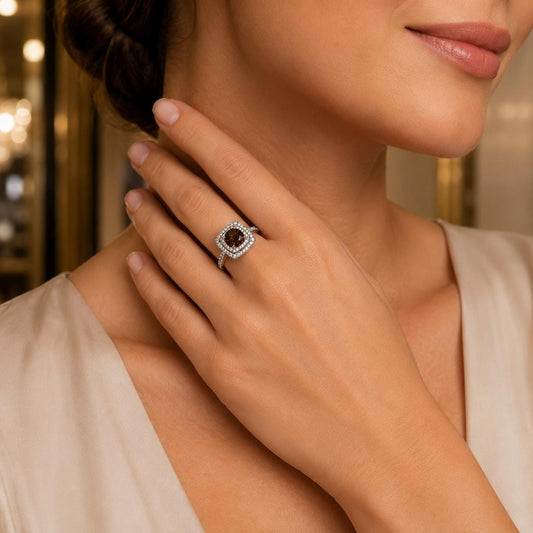 A close-up of a woman's hand wearing a diamond ring, with a blurred background.
