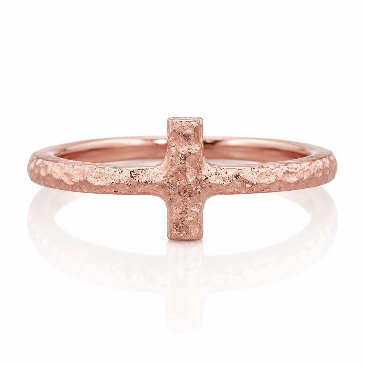 A rose gold ring with a textured, rough surface and a small, square-shaped cross-shaped element in the center.