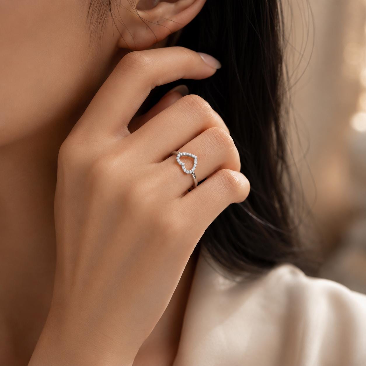 A close-up of a person's hand wearing a ring with a heart-shaped design.