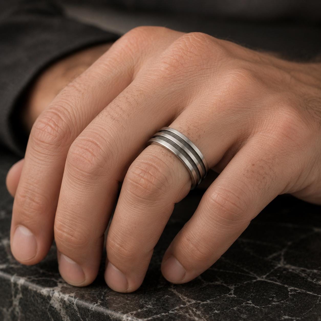 A close-up image of a person's hand wearing a silver ring with three concentric bands.
