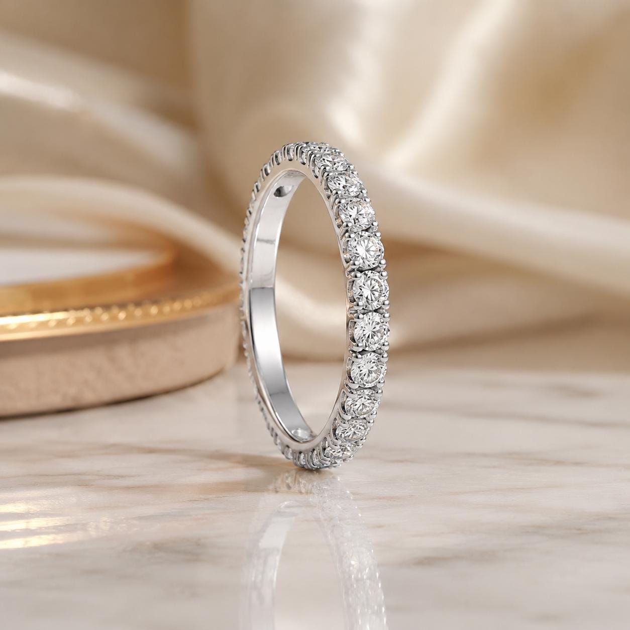 A diamond-encrusted ring with a row of diamonds set in a silver band is displayed on a marble surface.