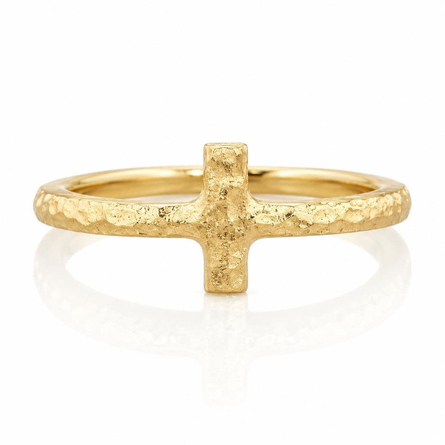 A gold ring with a large, textured cross-shaped gemstone in the center.