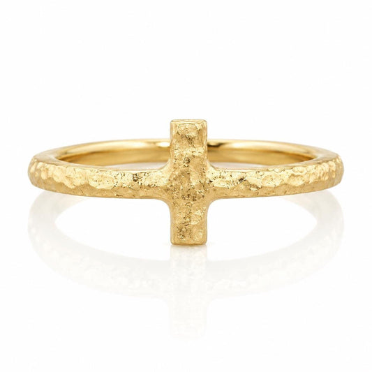 A gold ring with a large, textured cross-shaped gemstone in the center.