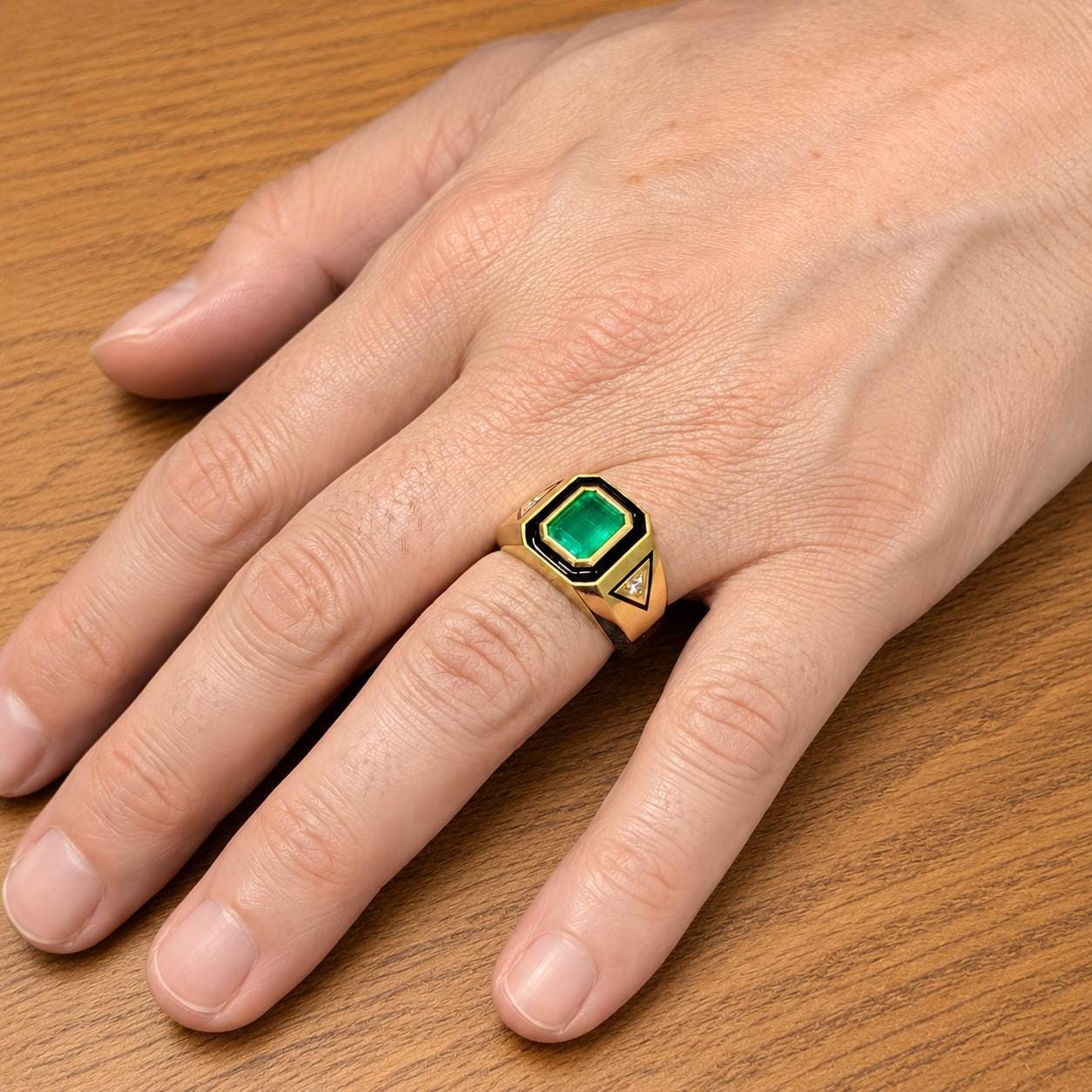 A close-up image of a person's hand wearing a gold ring with a green gemstone.