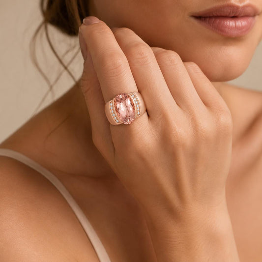 A close-up of a woman's hand wearing a large, pink gemstone ring with a gold band.