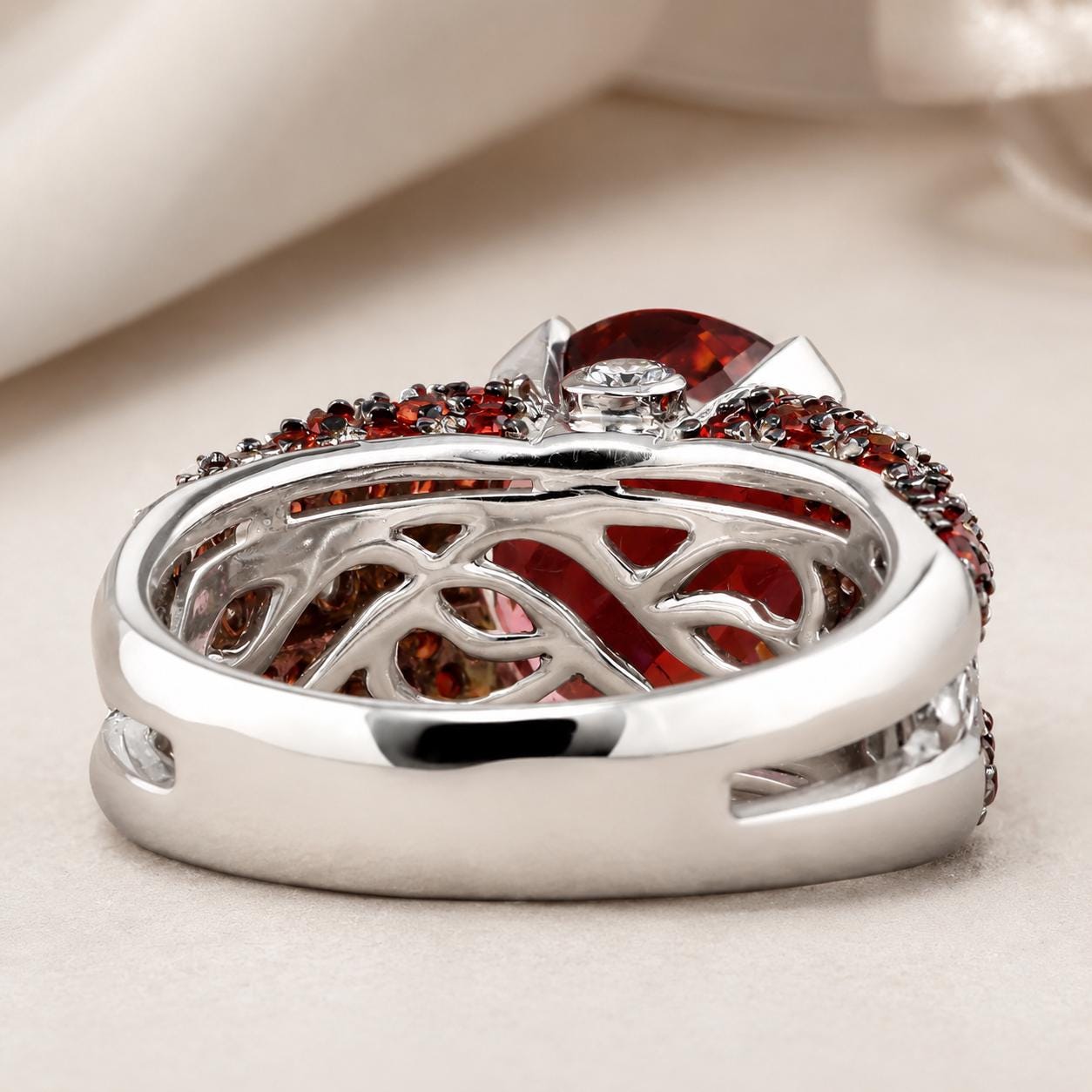 A silver ring with a large red gemstone and smaller red gemstones set in a decorative pattern.