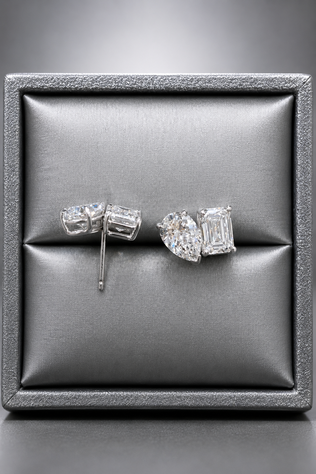 A display case containing a pair of diamond earrings, with the earrings featuring a large diamond and a smaller diamond.