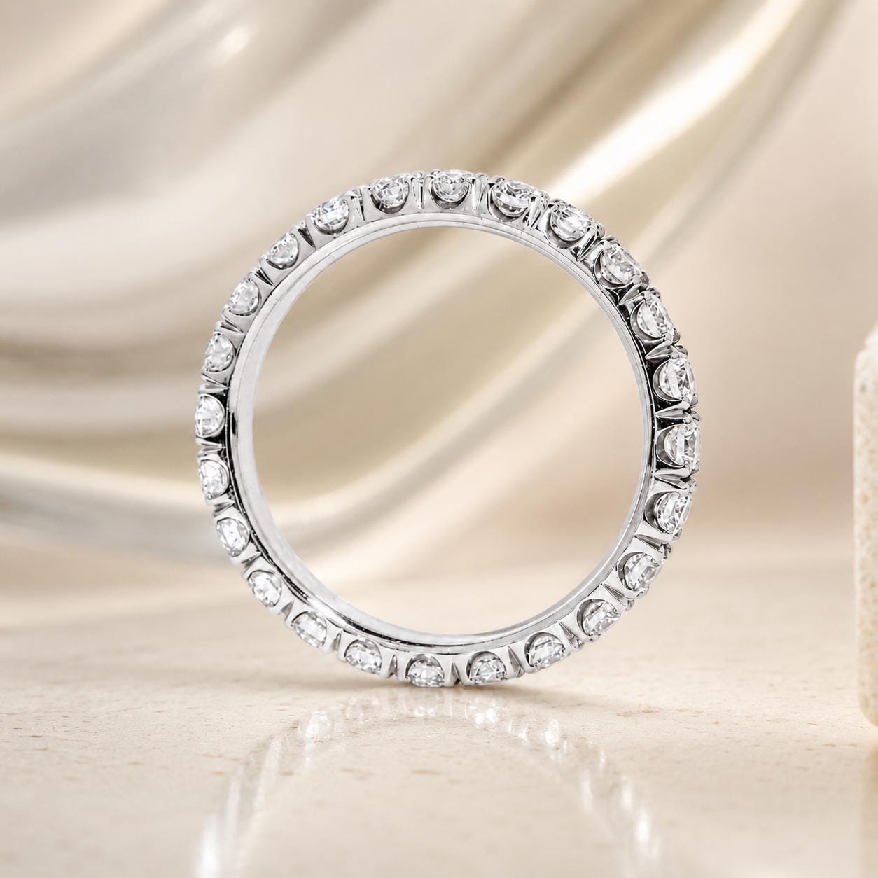 A diamond-encrusted ring is displayed against a light beige background.