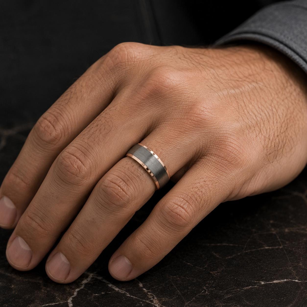 A close-up image of a hand wearing a ring on the ring finger.