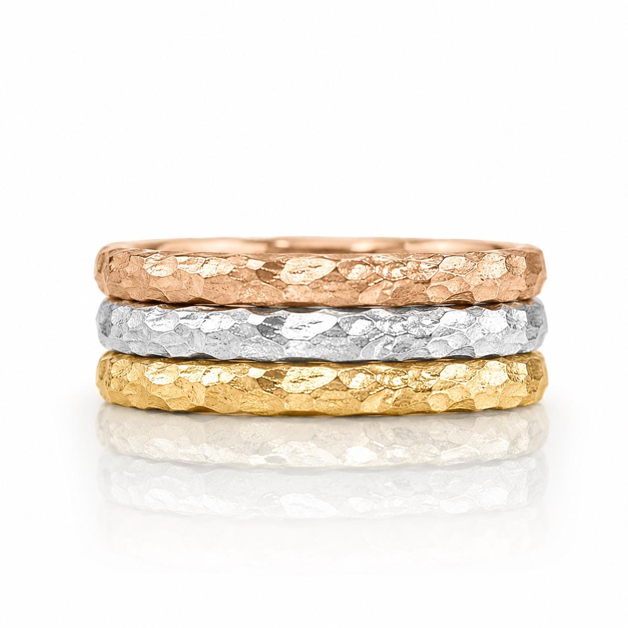 A stack of three rings with different textures and colors, including gold, silver, and copper.
