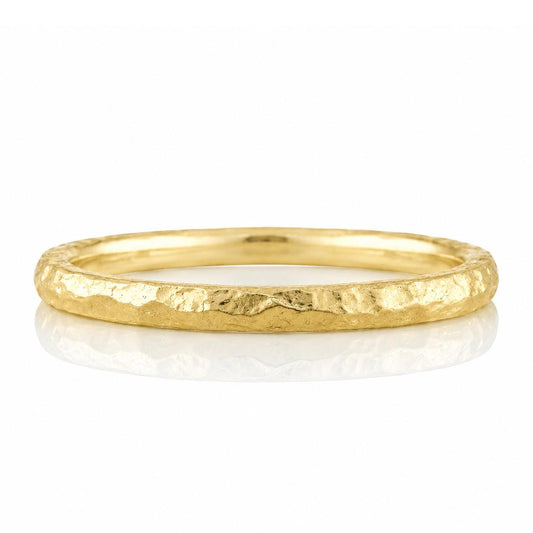 A gold ring with a textured surface and a smooth inner surface, placed on a white background.