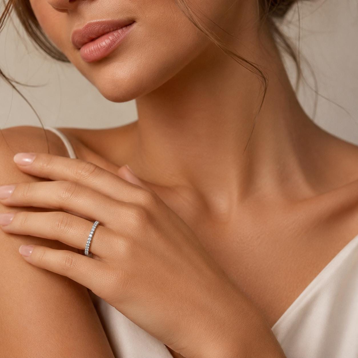 A close-up of a woman's hand wearing a diamond ring, with her chin and neck visible.