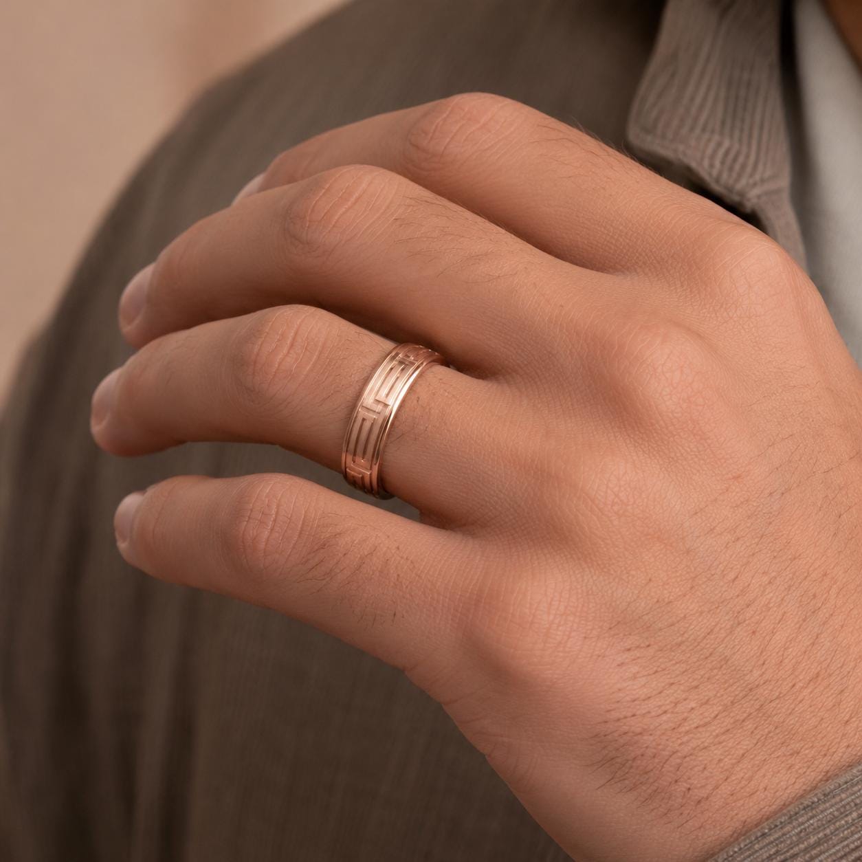A close-up of a person's hand wearing a gold ring on the ring finger.