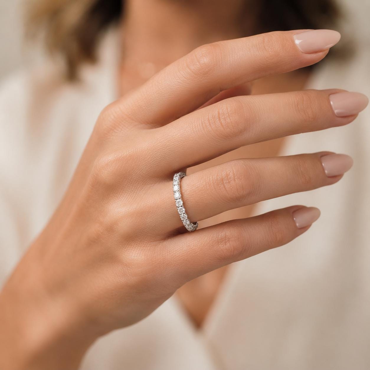 A close-up of a person's hand wearing a diamond ring on the ring finger.