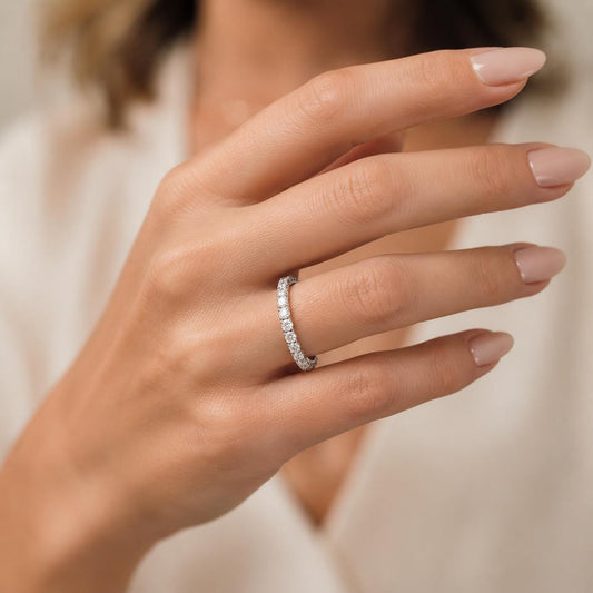A close-up of a person's hand wearing a diamond ring on the ring finger.
