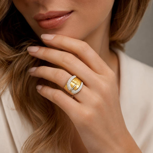 A close-up of a woman's hand wearing a gold ring with a large diamond.