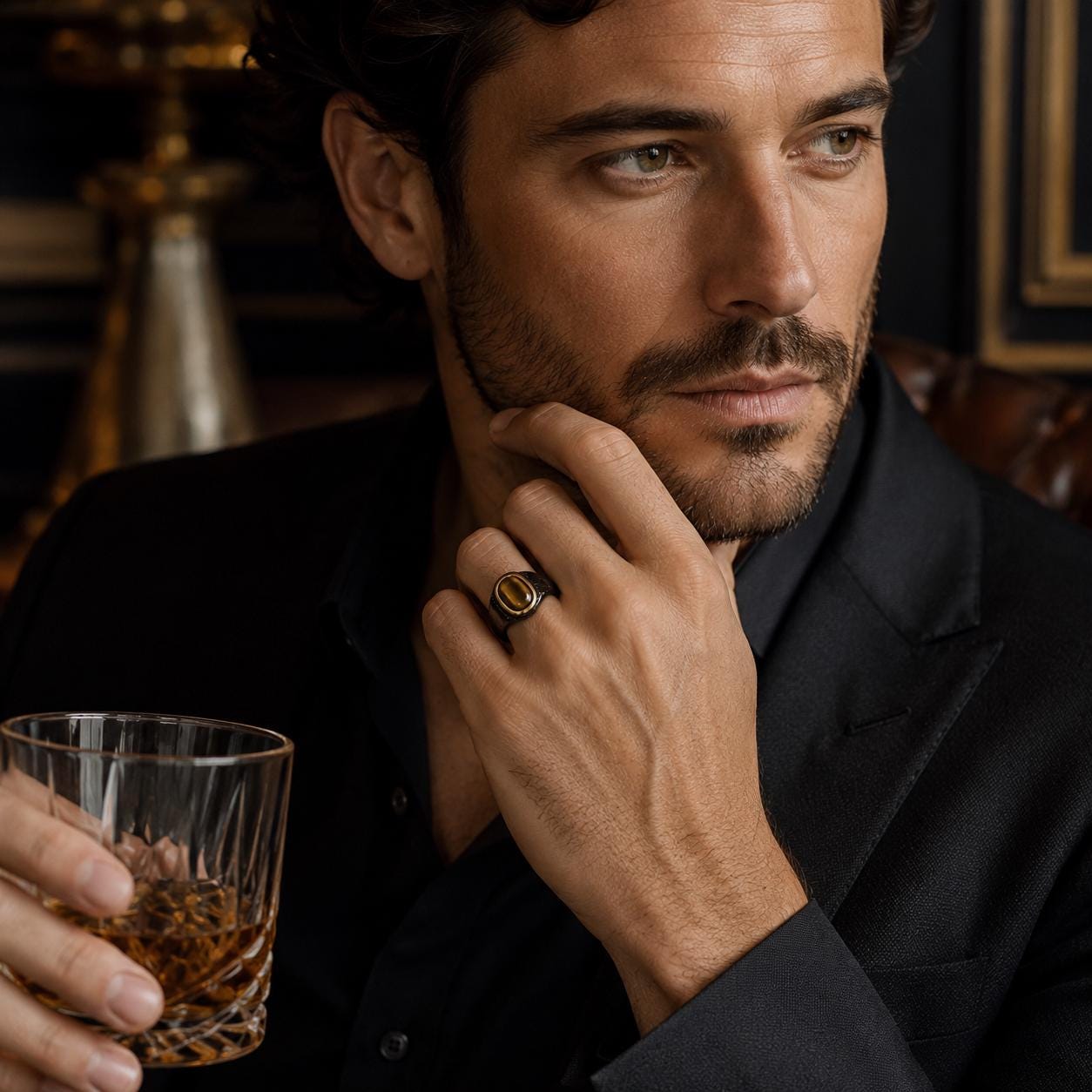 A man in a black suit holding a glass of whiskey, with a thoughtful expression on his face.