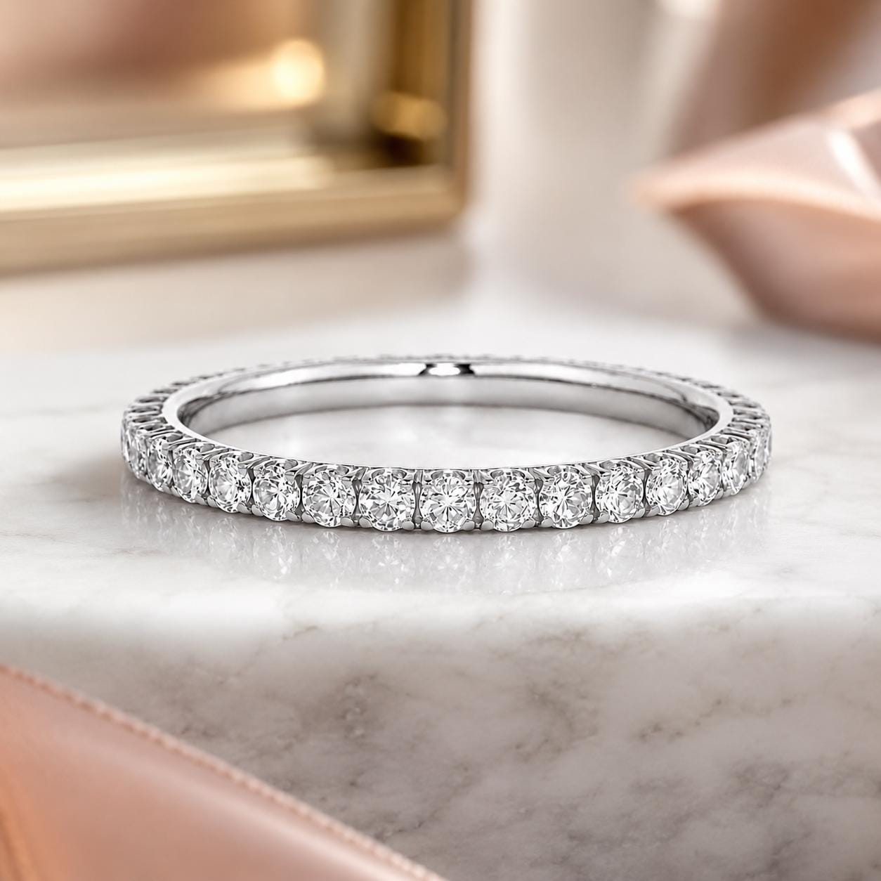 A diamond band ring with a row of round diamonds set in a silver band, resting on a marble surface.