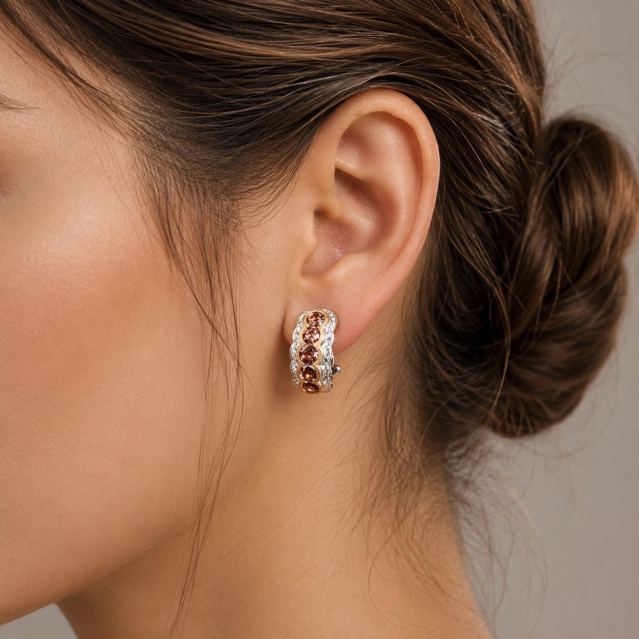 A close-up of a woman's ear wearing a pair of earrings with colorful gemstones.
