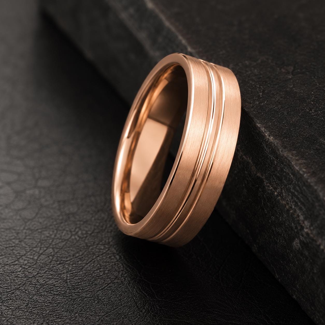 A gold-colored ring is resting on a black surface.