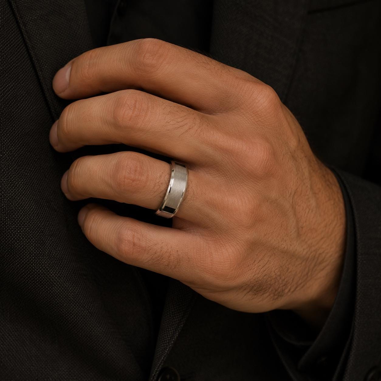 A close-up image of a hand wearing a silver ring on the ring finger.