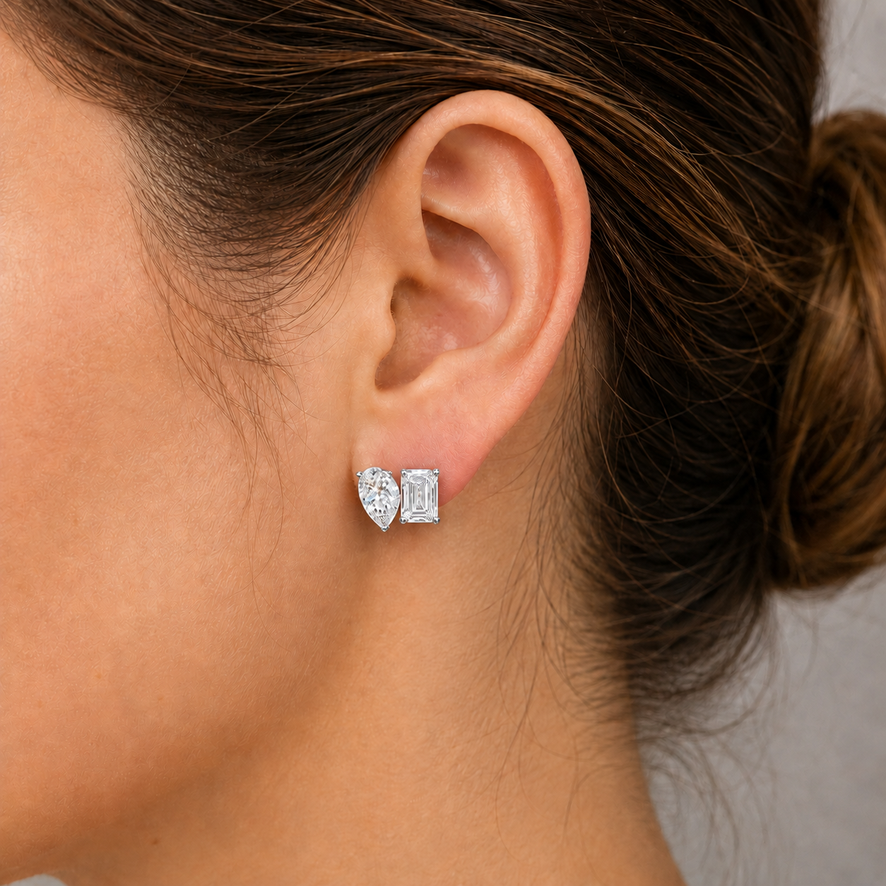 A close-up of a woman's ear wearing a pair of diamond earrings.