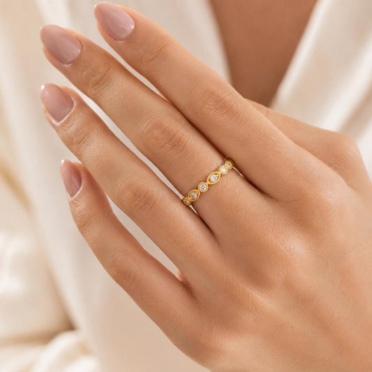 A close-up of a person's hand wearing a gold ring with small diamonds.