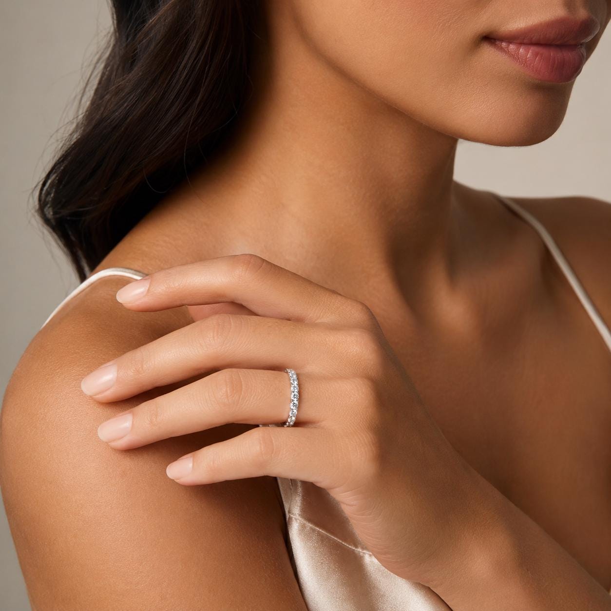 A close-up of a woman's hand wearing a diamond ring on her finger, with her hair visible behind her.